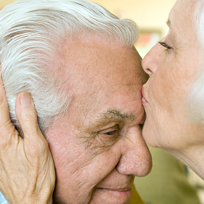 senior woman kissing her husband's forehead