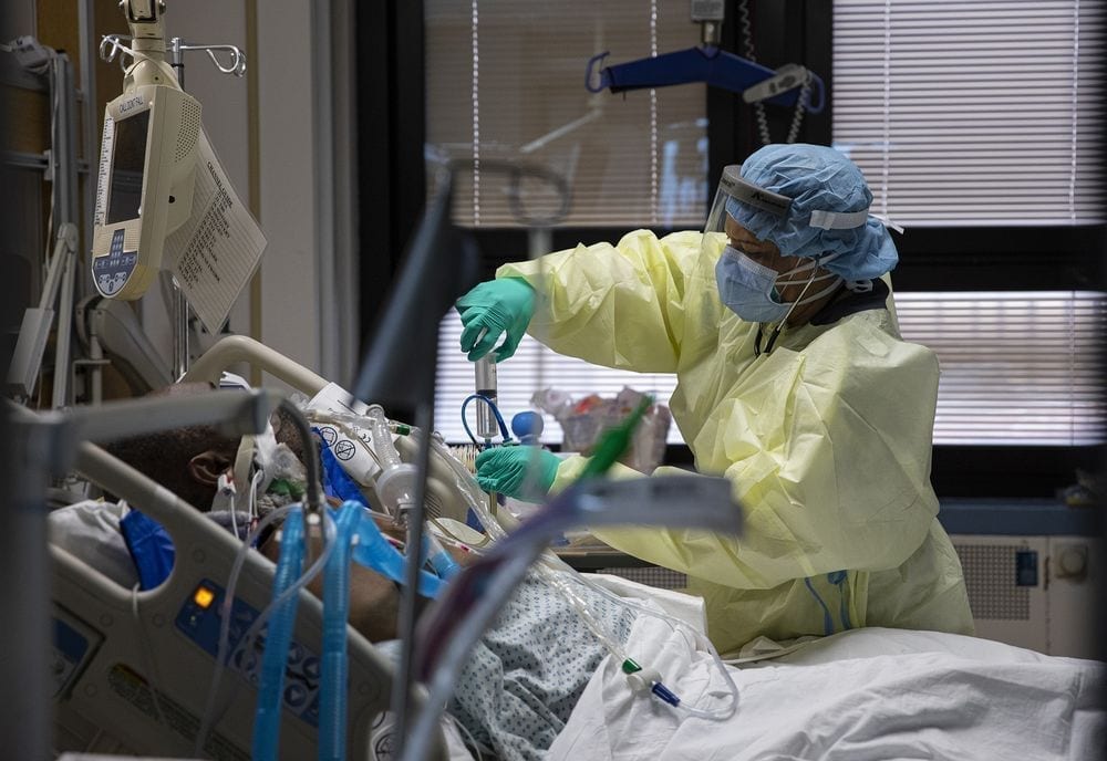 a nurse wearing PPE caring for a patient