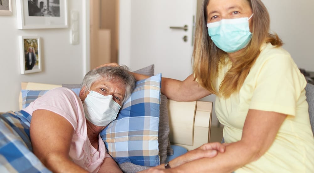 caregiver helping elderly mother with masks on