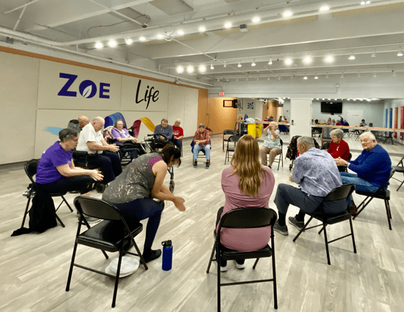 group of seniors sitting in chairs in a circle exercising