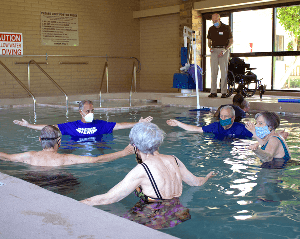 group swim class with seniors in pool wearing masks during pandemic
