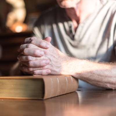 senior with his hands clasped on a bible