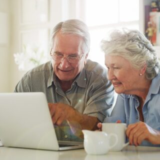 senior couple drinking coffee while looking at their computer