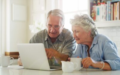 senior couple drinking coffee while looking at their computer