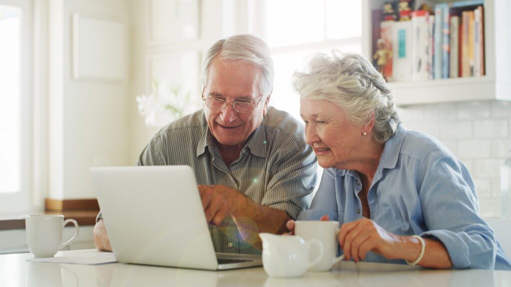 senior couple drinking coffee while looking at their computer