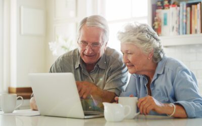 senior couple drinking coffee while looking at their computer